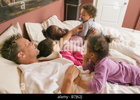 AA mamma, papà caucasico, Mulatto bambini, ragazzo 1,5 anni, ragazza 3 anni, ragazza 6 anni. In letto. Foto Stock