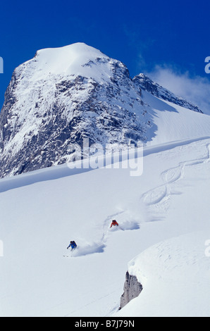 Due giovani uomini sci untracked polvere in figura 8's, Bugaboo Glacier Parco Provinciale, British Columbia, Canada Foto Stock