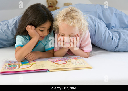 Due bambine leggendo un libro a letto Foto Stock