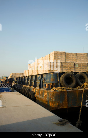 Importazione, operai lo scarico dei pallet di cemento iraniano, erogata dalla chiatta. presso la banchina di Al Sharjah, Dubai, UAE Foto Stock
