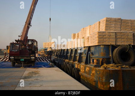 Importazione di materiali da costruzione, operai che scaricano pallet di cemento iraniano, consegnati da chiatta alla banchina di al Sharjah, Dubai, Emirati Arabi Uniti Foto Stock