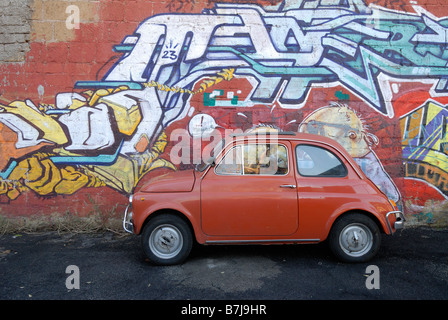 Italiano iconica piccolo rosso Fiat 500 auto contro contemporaneo sfondo graffiti roma italia Foto Stock