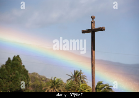 Un bellissimo arcobaleno e una croce cristiana. Foto Stock