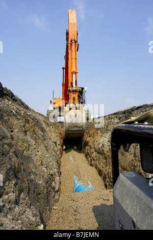 Riempimento escavatore nella sezione di tubo drenante con sporcizia; Canada Ontario, Hamilton (Compostaggio) Foto Stock