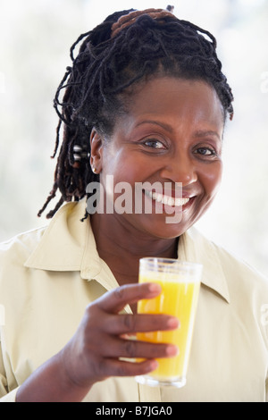 Senior donna a bere il succo d'arancia fresco Foto Stock