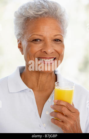 Adulti Senior tenendo un bicchiere di succo d'arancia fresco, sorridente verso la telecamera Foto Stock