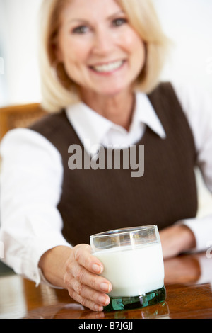 Senior donna tenendo un bicchiere di latte, sorridente verso la telecamera Foto Stock