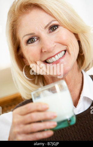 Senior donna tenendo un bicchiere di latte, sorridente verso la telecamera Foto Stock