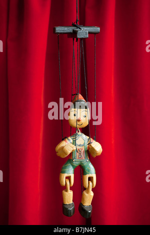 Pinocchio marionetta di legno si blocca nella parte anteriore del sipario rosso Foto Stock