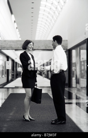 Executive femmina nella hall si stringono la mano con connettore maschio di tipo executive, ufficio Foto Stock