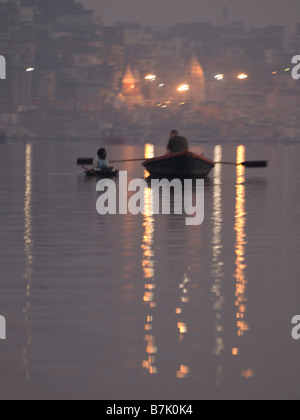 Una barca uomo righe la sua barca di mostrare ai visitatori la vita lungo il fiume sacro Gange, un importante sito pilgrimge per gli indù. Foto Stock