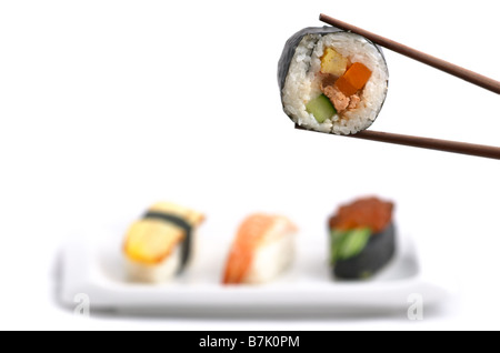 Il cibo giapponese: deliziosi Futomaki tenere con bacchette e la selezione di tre nigiri shushes isolati su sfondo bianco Foto Stock