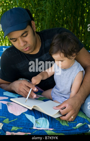 Ispanico padre e figlio bambino disegno mentre godendo l'estate nel giardino di casa Foto Stock