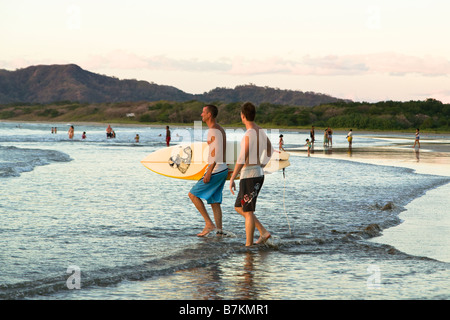 Surfers wading in acqua con la tavola da surf sulla spiaggia di Playa Tamarindo, Costa Rica. Foto Stock