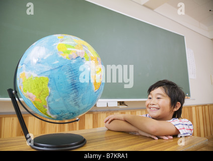 Scuola elementare boy guardando il globo terrestre Foto Stock