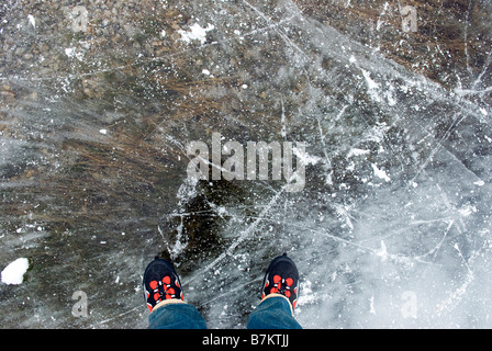 Persona con pattini in piedi sul lago ghiacciato, vista in elevazione Foto Stock