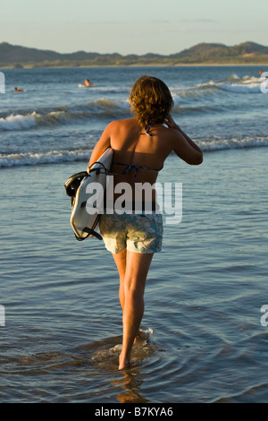 Surfista con la tavola da surf a piedi sulla spiaggia di Playa Tamarindo, Costa Rica. Foto Stock