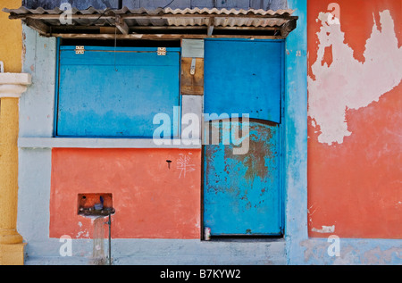 Porta blu e pareti di colore arancione con peeling vernice su una strada laterale off i mercati occupato su Isla Mujeres, Messico. Foto Stock