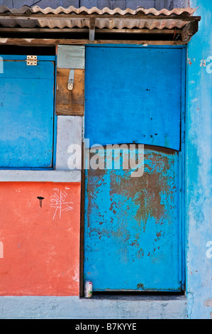 Un peeling porta blu su di una tranquilla strada laterale nei mercati su Isla Mujeres Messico con arancia e pareti bianche. Foto Stock