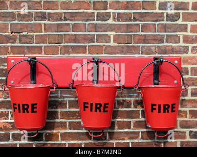 Antique fire bucket in una stazione ferroviaria, fissato a una parete Foto Stock