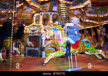 Bambino sfocata equitazione tradizionale illuminato Merry Go Round/giostra fairground ride, Winter Wonderland, Hyde Park, London, Regno Unito Foto Stock