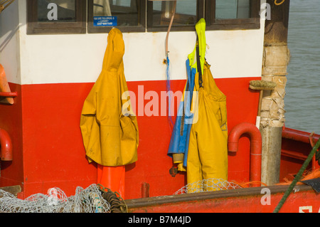 Fishermans giallo impermeabilizza appeso sul retro della timoneria di un commerciale barca da pesca indumenti impermeabili Foto Stock