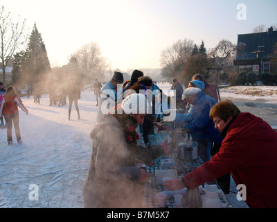 Gente che vende bevande calde e una zuppa ai partecipanti al pattinaggio Molentocht tour utilizzando uno stallo sul ghiaccio Foto Stock