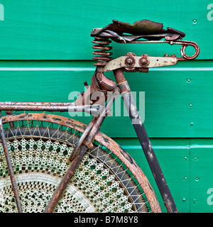 Un arrugginito e indossato vecchia bicicletta olandese appoggiata contro un verde luminoso capannone di legno, Arnhem, Paesi Bassi Foto Stock