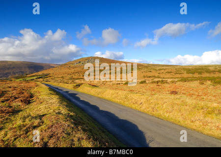 Una stretta via unica strada di campagna nei pressi di rocce Bonehill su Dartmoor con Chinkwell Tor a metà distanza Foto Stock