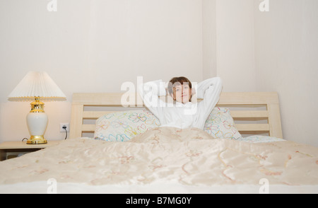 La ragazza su un letto è vestito in un bianco vestaglia età di 25 anni Foto Stock