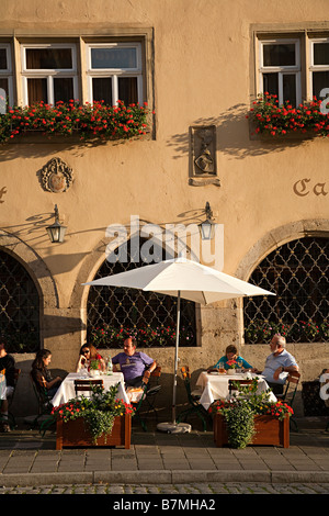 Persone bere ai tavoli fuori del ristorante nella piazza principale Rothernburg Germania Foto Stock