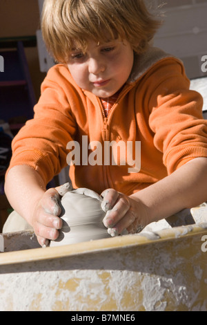 Bambino di nove anni lavora su un vaso utilizzando una ruota Foto Stock