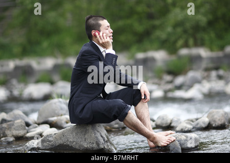 Imprenditore parlando al cellulare al fiume Foto Stock