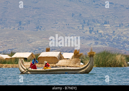 2 donne locali vestiti in abiti tradizionali su una canna barca ad una delle isole di canne sul lago Titicaca. Foto Stock