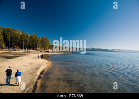 Un uomo e una donna a piedi lungo la spiaggia di Kings Beach Stato Area Ricreativa del Lago Tahoe California Foto Stock