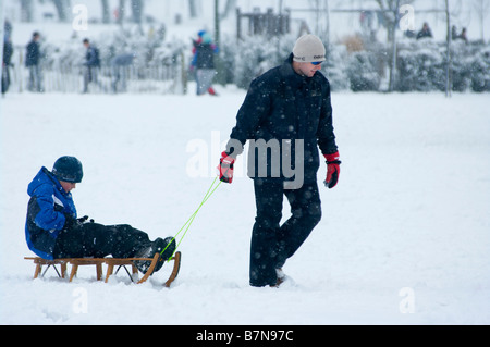 L'uomo persona tirando ragazzo su una slitta slitta nella neve Foto Stock