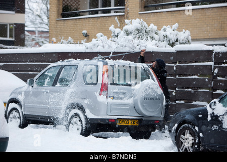 Una donna che pulisce la neve dalla sua auto a Muswell Hill Londra nord Foto Stock