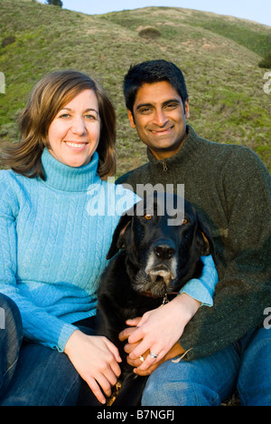 Giovane seduto con il cane all'aperto al tramonto in california sulla collina Foto Stock