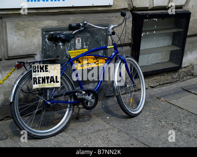 Una bicicletta vecchio stile parcheggiato a fianco di un edificio della città di mura con un cartello che dice "Noleggio bici". Foto Stock
