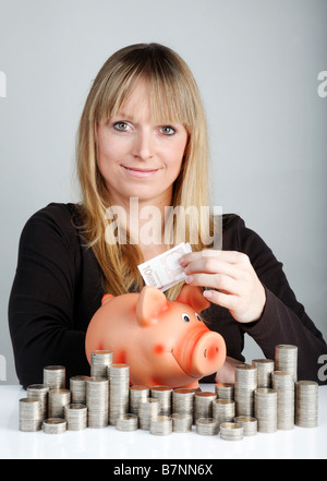 Giovane donna con un piggybank Foto Stock