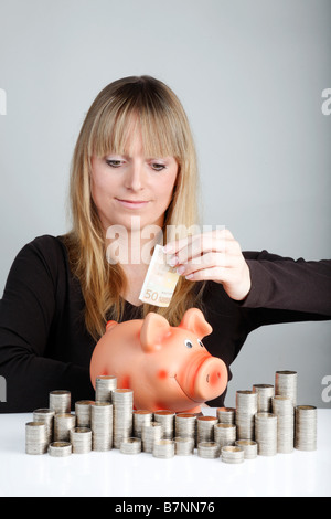 Giovane donna con un piggybank Foto Stock