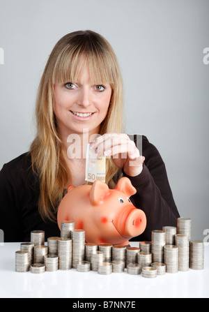 Giovane donna con un piggybank Foto Stock