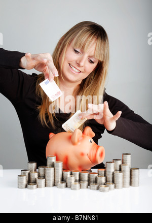Giovane donna con un piggybank Foto Stock