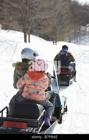 Famiglia a cavallo su motoslitte Foto Stock