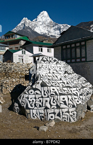 Una fede viva mantra o sacra sillabe essendo dipinta su un masso sul ciglio della strada nel villaggio di Pangboche Nepal Foto Stock