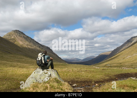 Hill walker ammirando il panorama verso il basso Lairig Gartain, Glen Coe, Lochaber, Scozia, maggio. Foto Stock