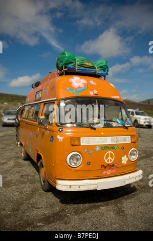 il camper-furgone personalizzato arancione degli anni '70 ha caricato i bagagli sul tetto, visti contro un cielo blu. REGNO UNITO Foto Stock