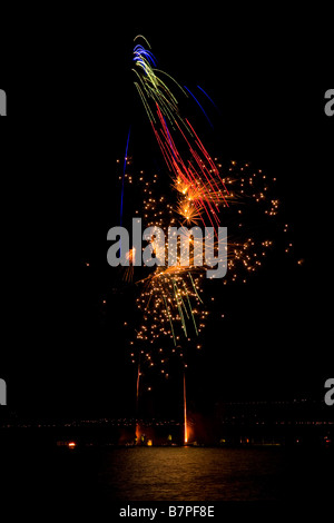 Fuochi d'artificio contro un cielo nero, rosso, verde e blu riflessa in un lago. Foto Stock