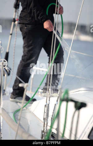 Sailor lavando la sua barca verso il basso dopo un viaggio in barca a vela. Foto Stock