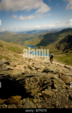 Walker on Path giù dal monte Snowdon Wales Glaslyn lago E Llyn Llydaw serbatoio in distanza Foto Stock